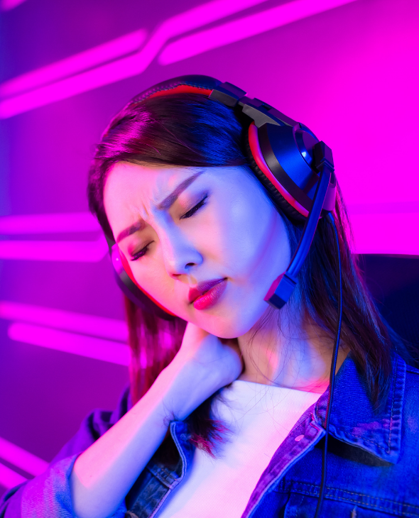 A photo of a woman wearing a gaming headset holding her neck in discomfort. Hyperion's human performance testing can benefit not only athletes but anyone with a profession or hobby that may be impacting their physical health.