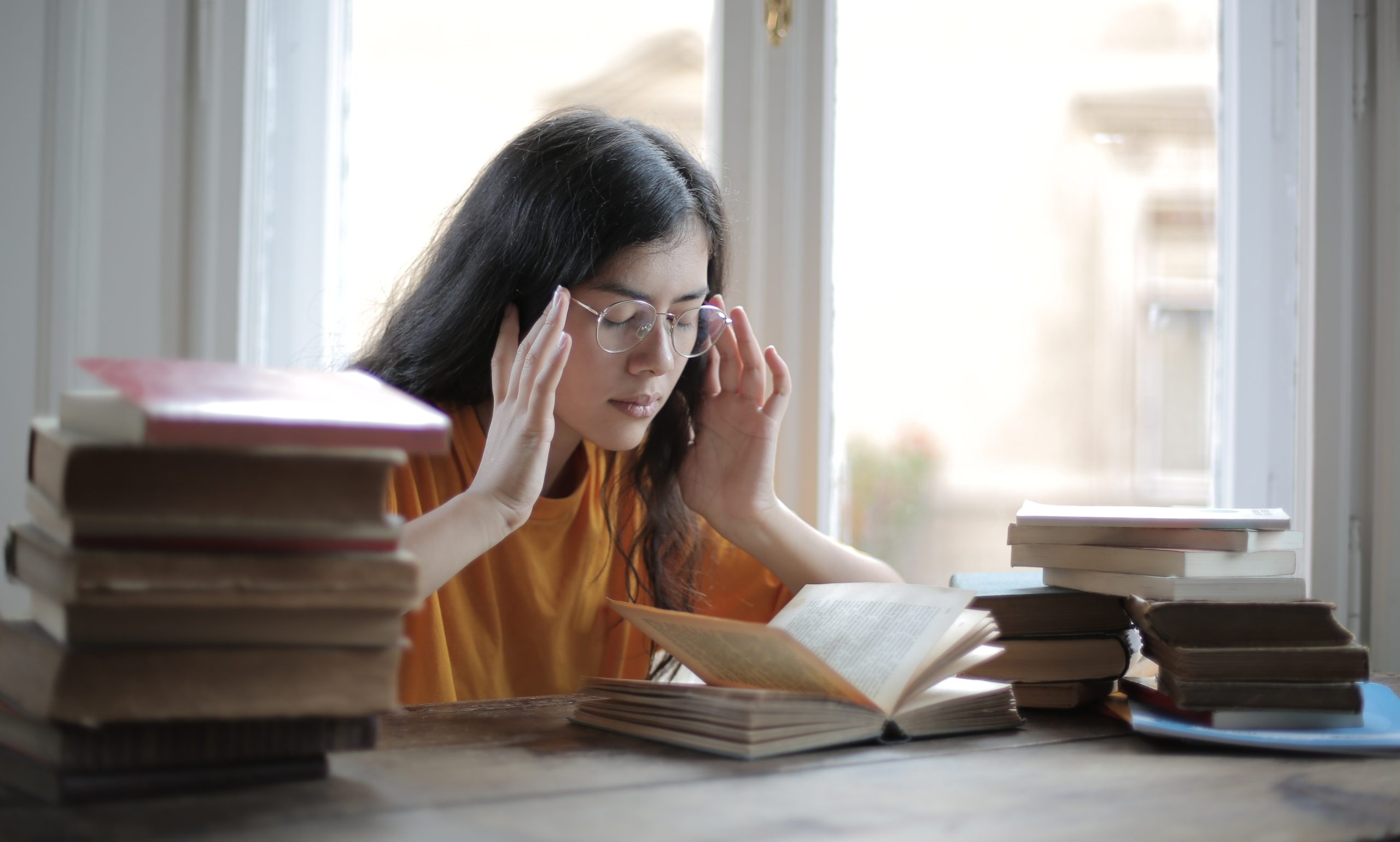 A photo of a female student with glasses struggling to concentrate on her work.